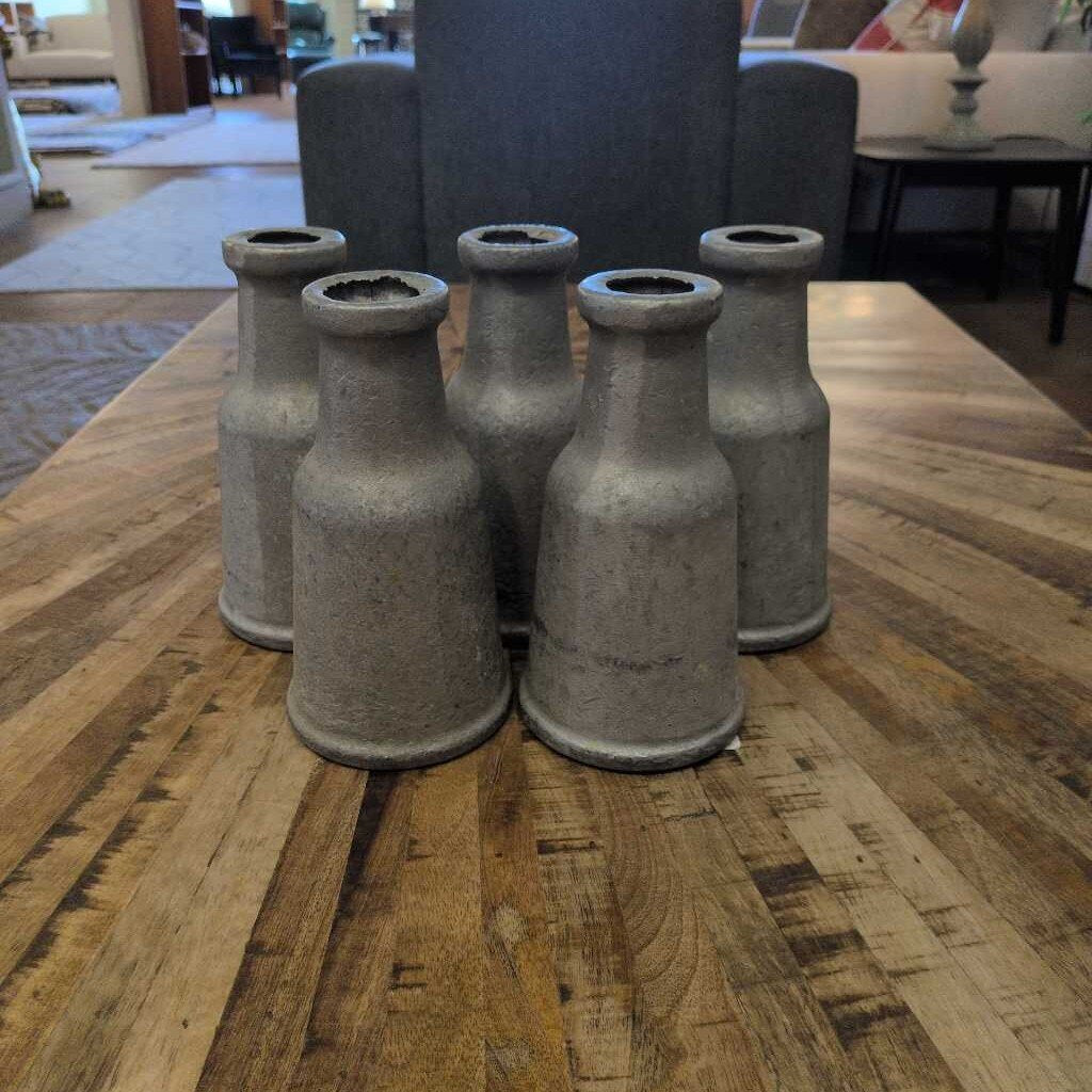 Set of five metallic bottle-shaped objects on a wooden table
