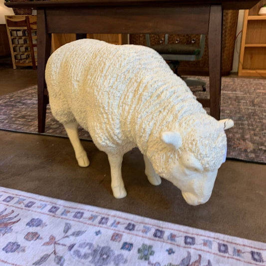 White sheep statue on a rug with a wooden table in the background