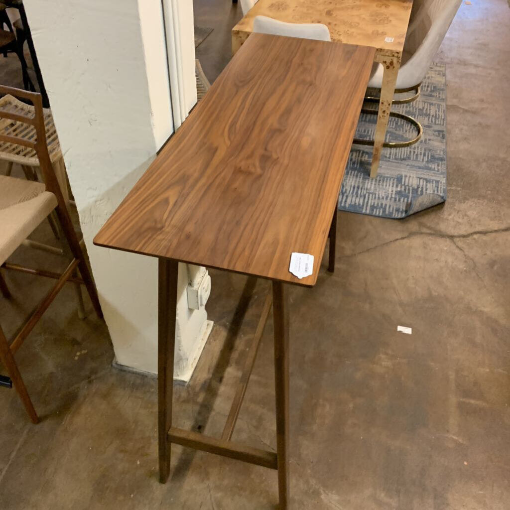 Wooden bar height table in a room with chairs and a rug.