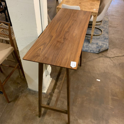 Wooden bar height table in a room with chairs and a rug.