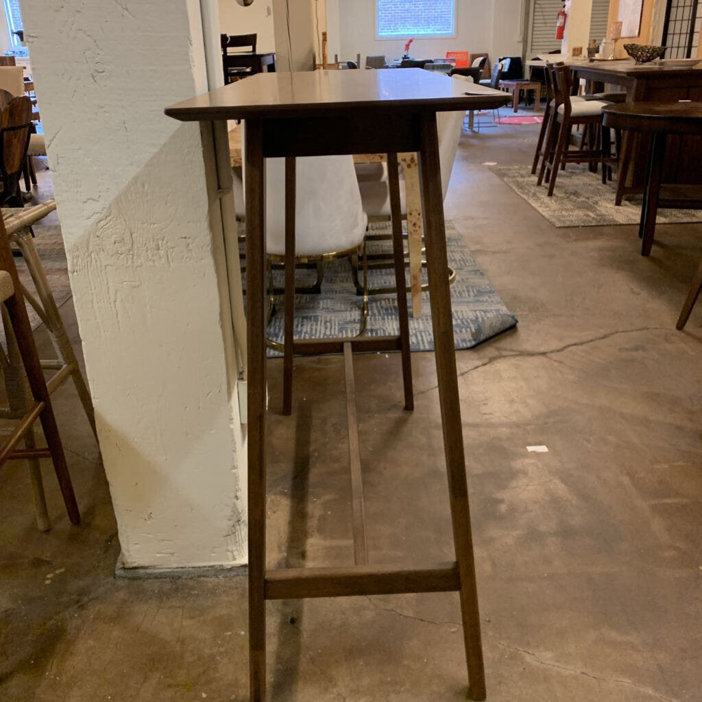 Wooden bar height table in a room with chairs and tables