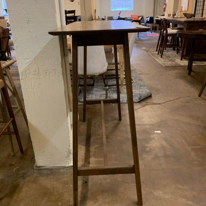 Wooden bar height table in a room with chairs and tables