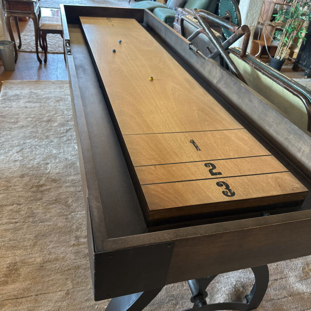 Shuffleboard table with wooden playing surface and metal frame in an indoor setting.