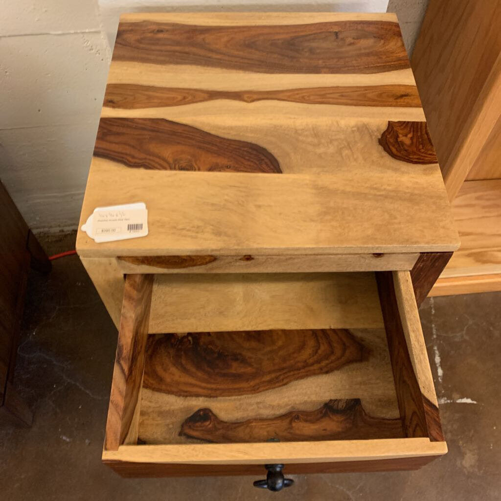 Wooden side table with a drawer, showing visible grain and texture.