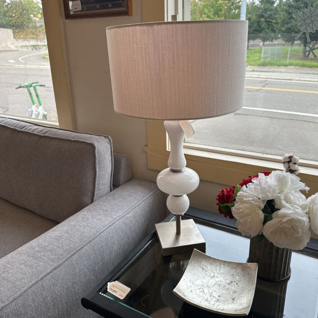 Living room with a gray sofa, lamp, and decorative items near a window.