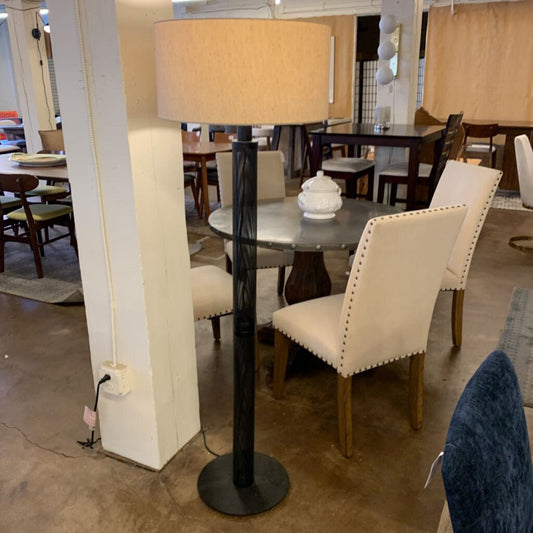 Dining room with a tall floor lamp, round table, and chairs in a showroom setting.