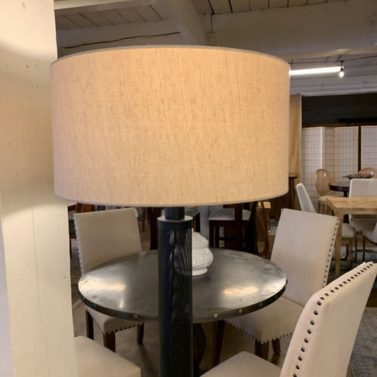 Dining room with a large lampshade on a table, chairs, and a neutral color scheme.