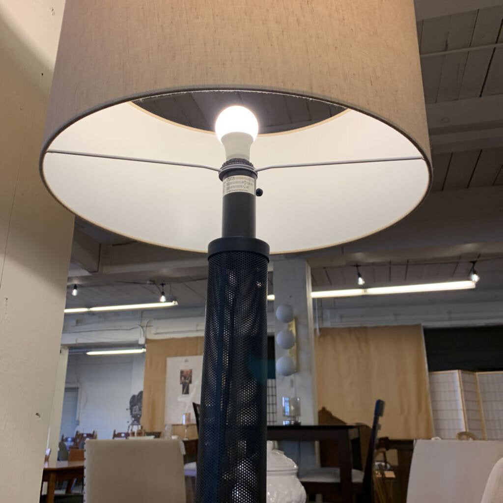 Close-up of a lamp with a beige shade in an indoor setting