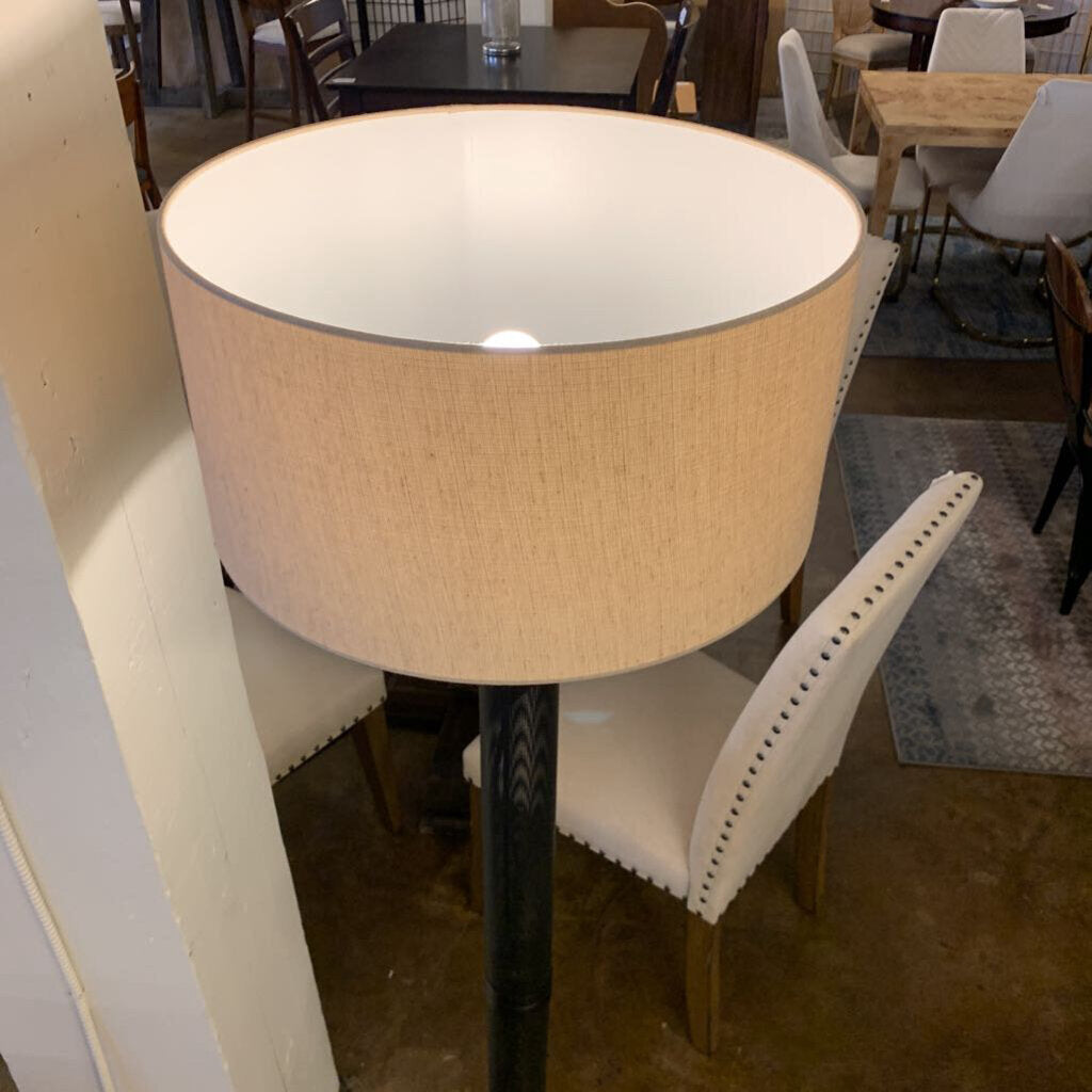 Round table with a beige lampshade in a room with chairs and tables.