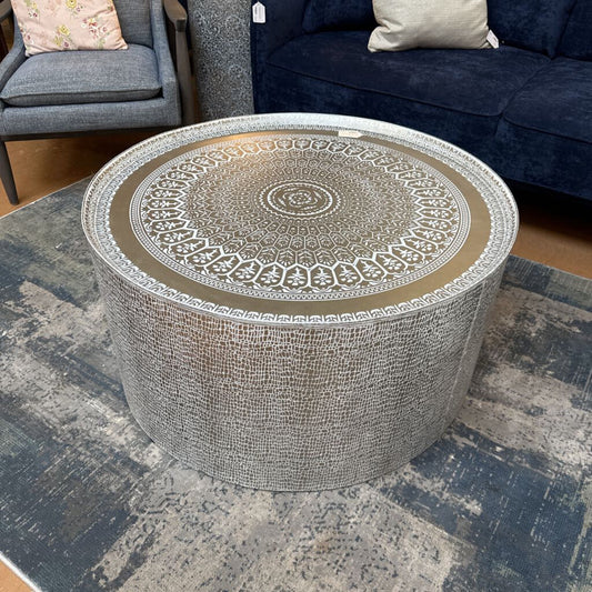 Round decorative table with intricate design on a textured rug