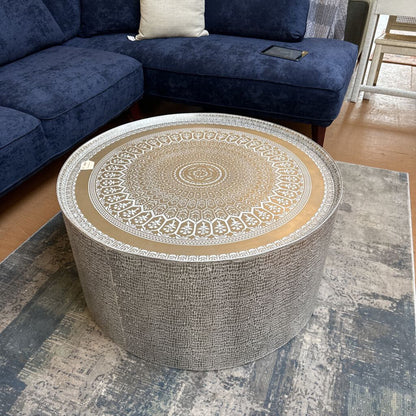 Round coffee table with decorative top in a living room setting