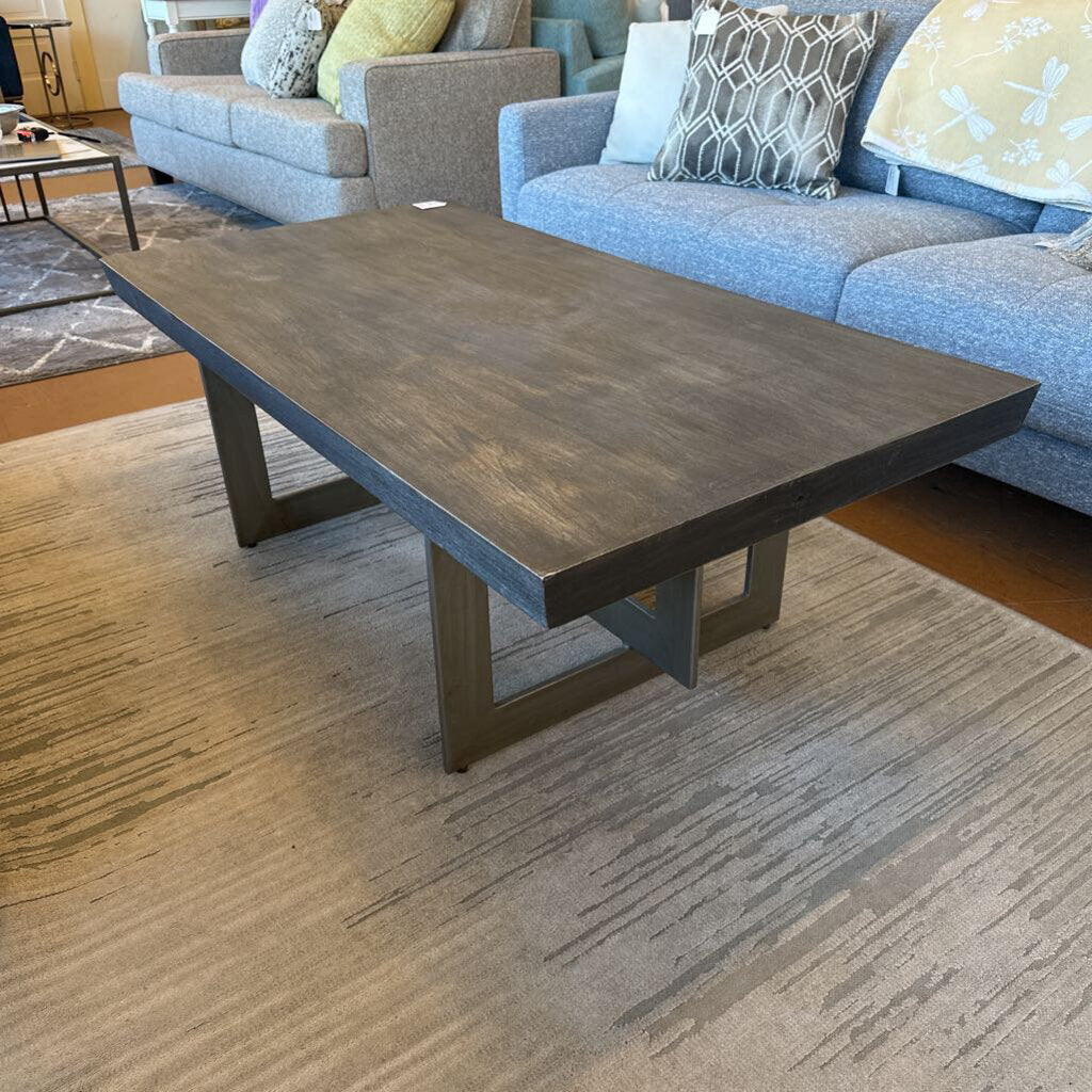 Wooden coffee table in a living room setting with a sofa and cushions.
