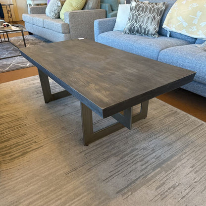 Wooden coffee table in a living room setting with a sofa and cushions.