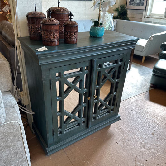 Dark green cabinet with decorative elements in a living room setting