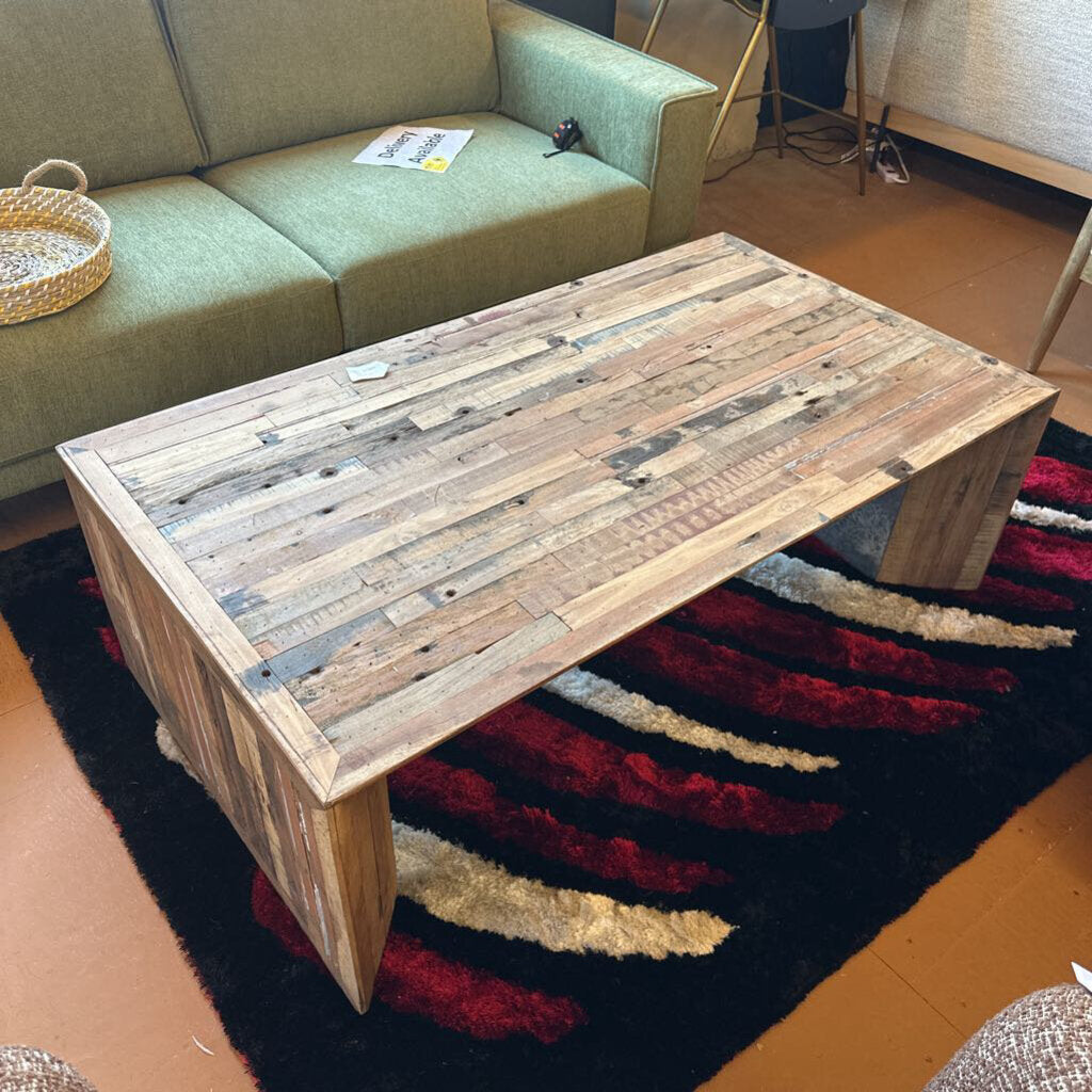 Wooden coffee table with a striped rug underneath in a living room setting.