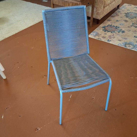 Blue wire chair on a brown floor with a patterned rug in the background