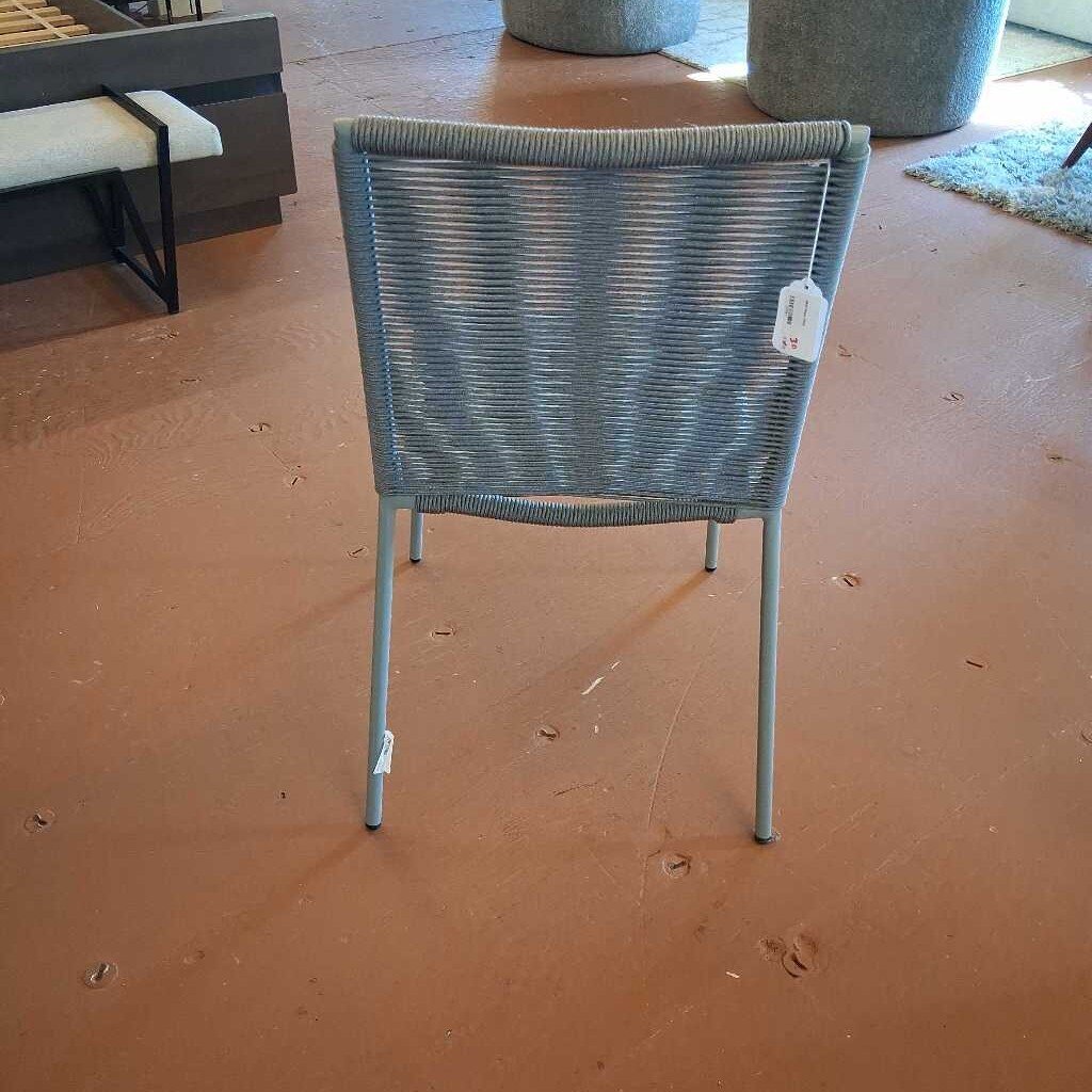 Blue wicker chair with a tag on a brown floor