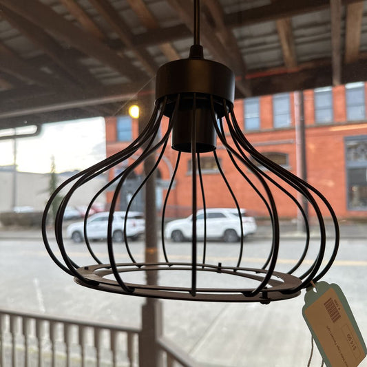 Black wire pendant light with a tag in front of a blurred street scene