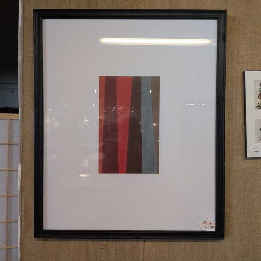 Framed abstract art piece with vertical stripes on a textured wall.