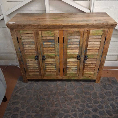 Wooden cabinet with shutters and black handles on a stone floor.