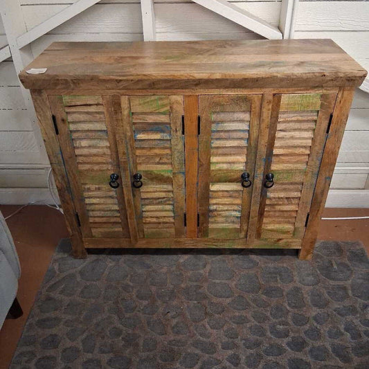 Wooden cabinet with shutters and black handles on a stone floor.