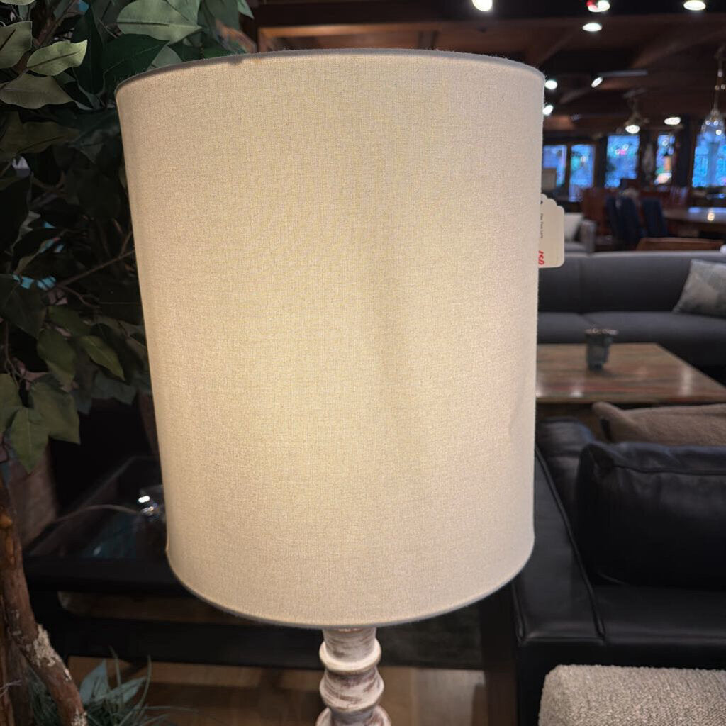 Beige lampshade on a wooden base with a blurred indoor setting in the background