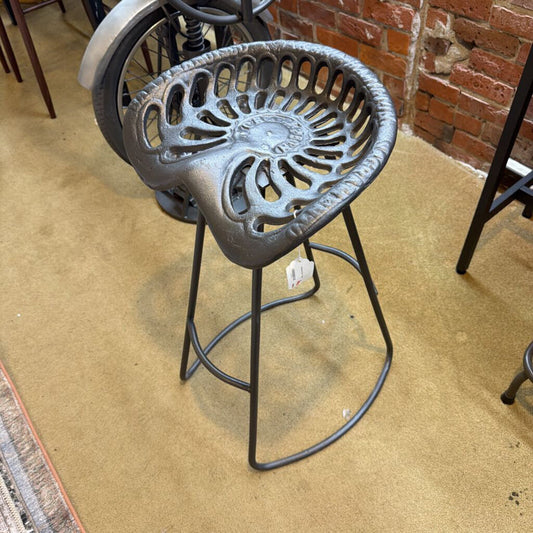 Decorative metal stool with intricate design on a concrete floor.