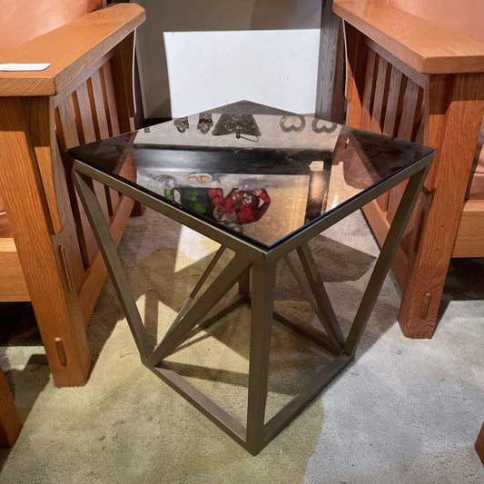 Small metal table with a glass top in a room with wooden furniture.