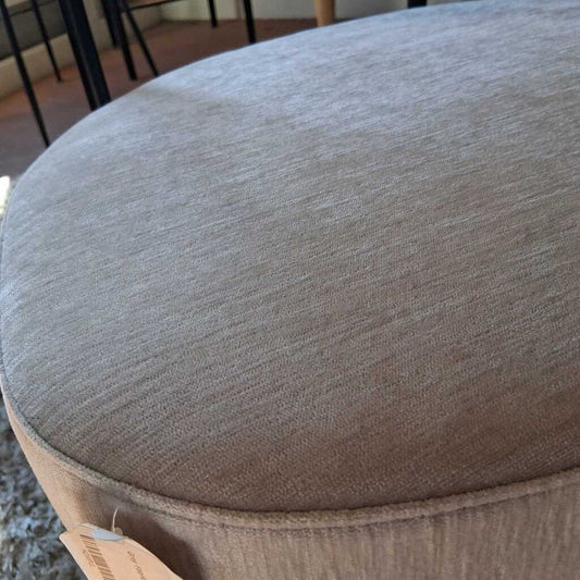 Close-up of a textured gray cushion with a brand tag on a blurred background