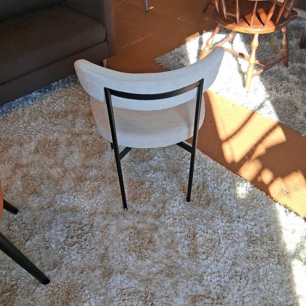 White chair with black legs on a textured carpet