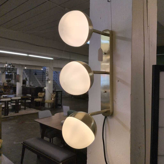 Modern wall-mounted light fixture with three spherical lights in a casual dining area.