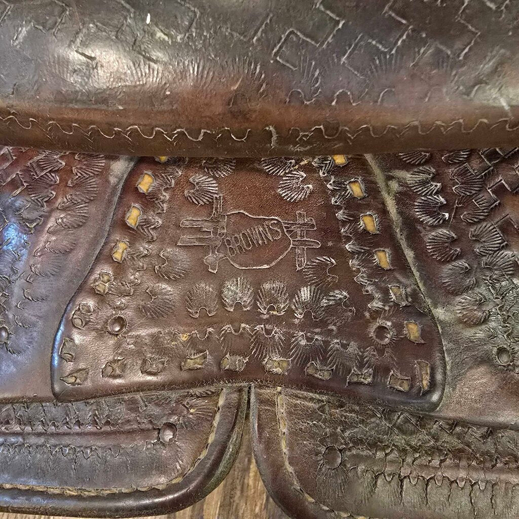 Close-up of a brown leather saddle with intricate patterns and a brand logo.