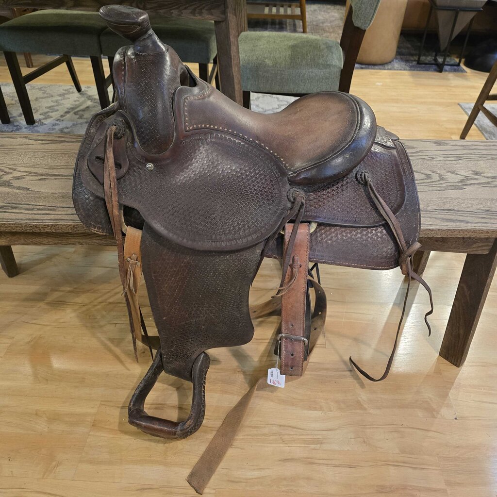 Brown leather saddle on a wooden bench with chairs in the background