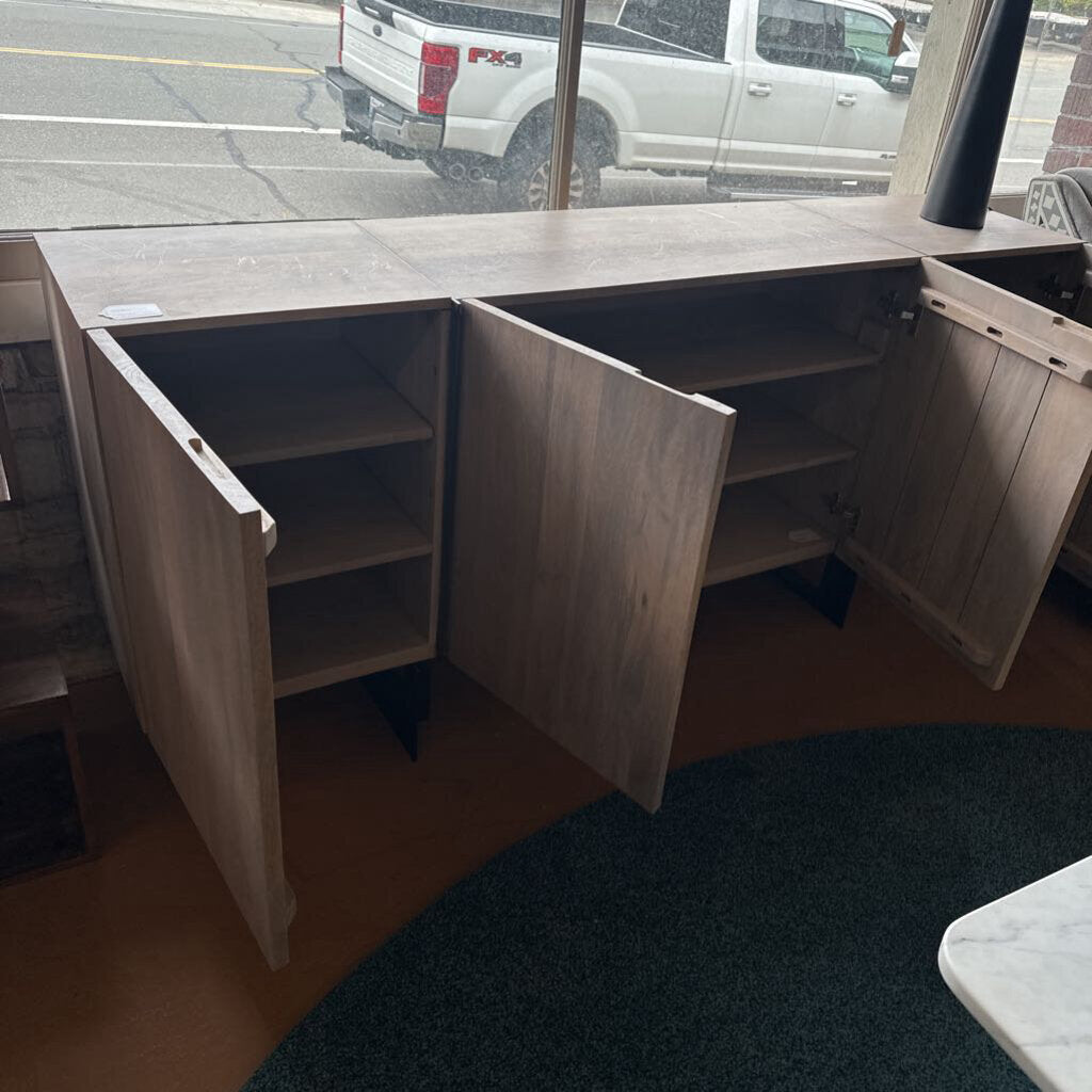 Wooden storage unit with open doors in a room with a truck visible through a window.