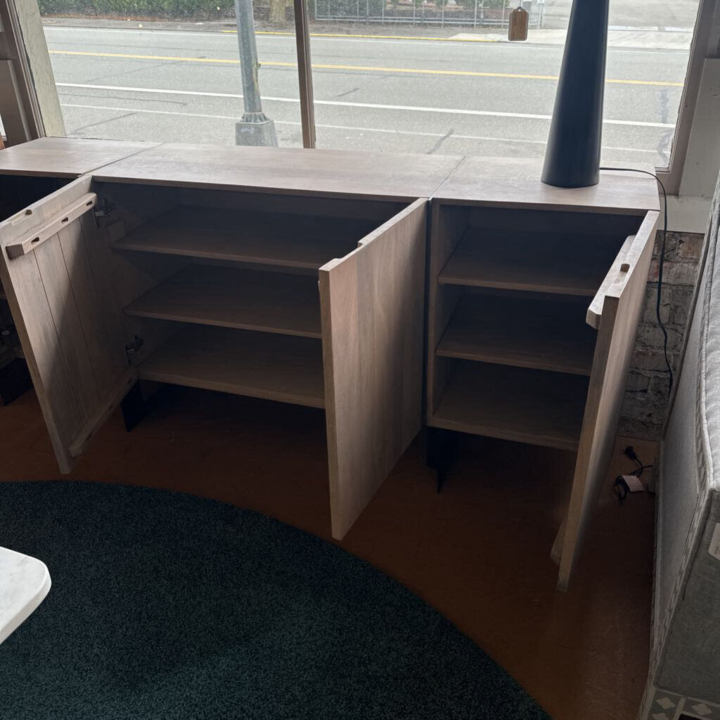 Wooden L-shaped desk with open shelves in a room with a window.