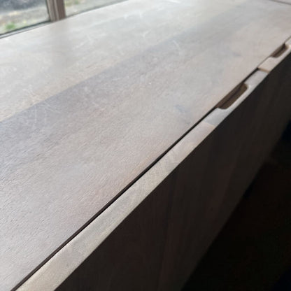 Close-up of a wooden surface with a window in the background