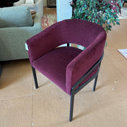 Purple chair on a cardboard floor with a gray sofa and plant in the background
