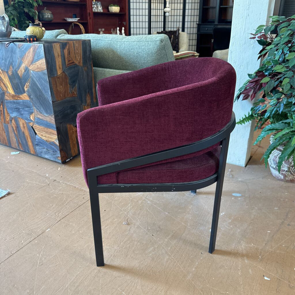 Maroon chair with black frame on a wooden floor in an indoor setting