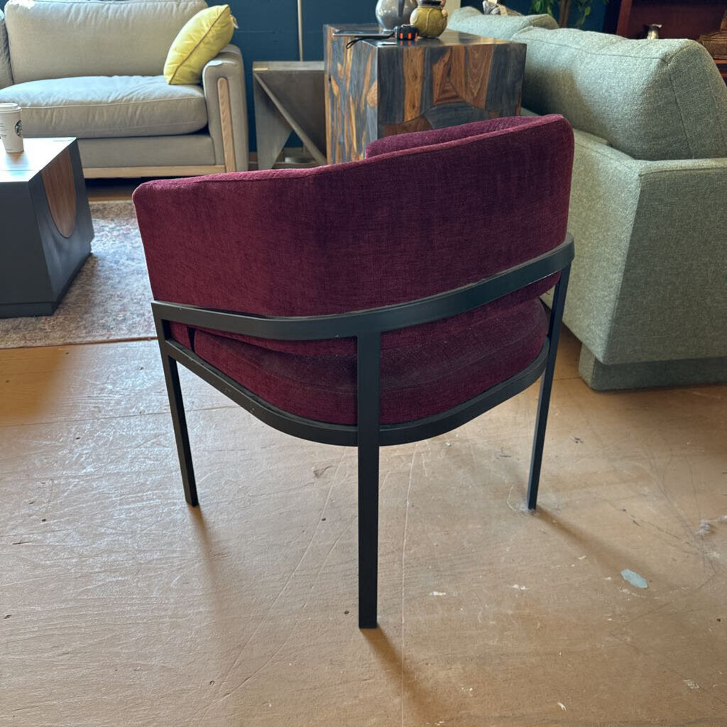 Maroon chair with black frame on a wooden floor, surrounded by furniture.