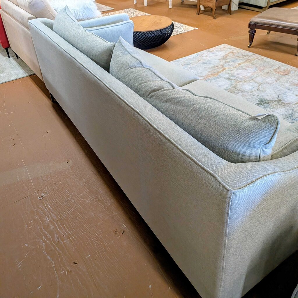 Light gray sectional sofa in a room with wooden flooring.