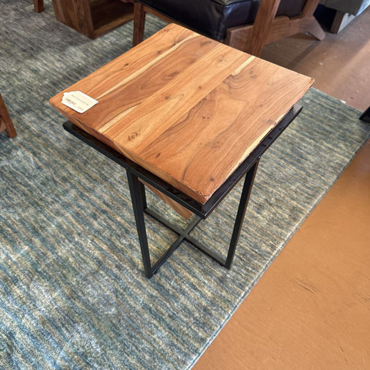 Wooden side table with metal legs on a carpeted floor