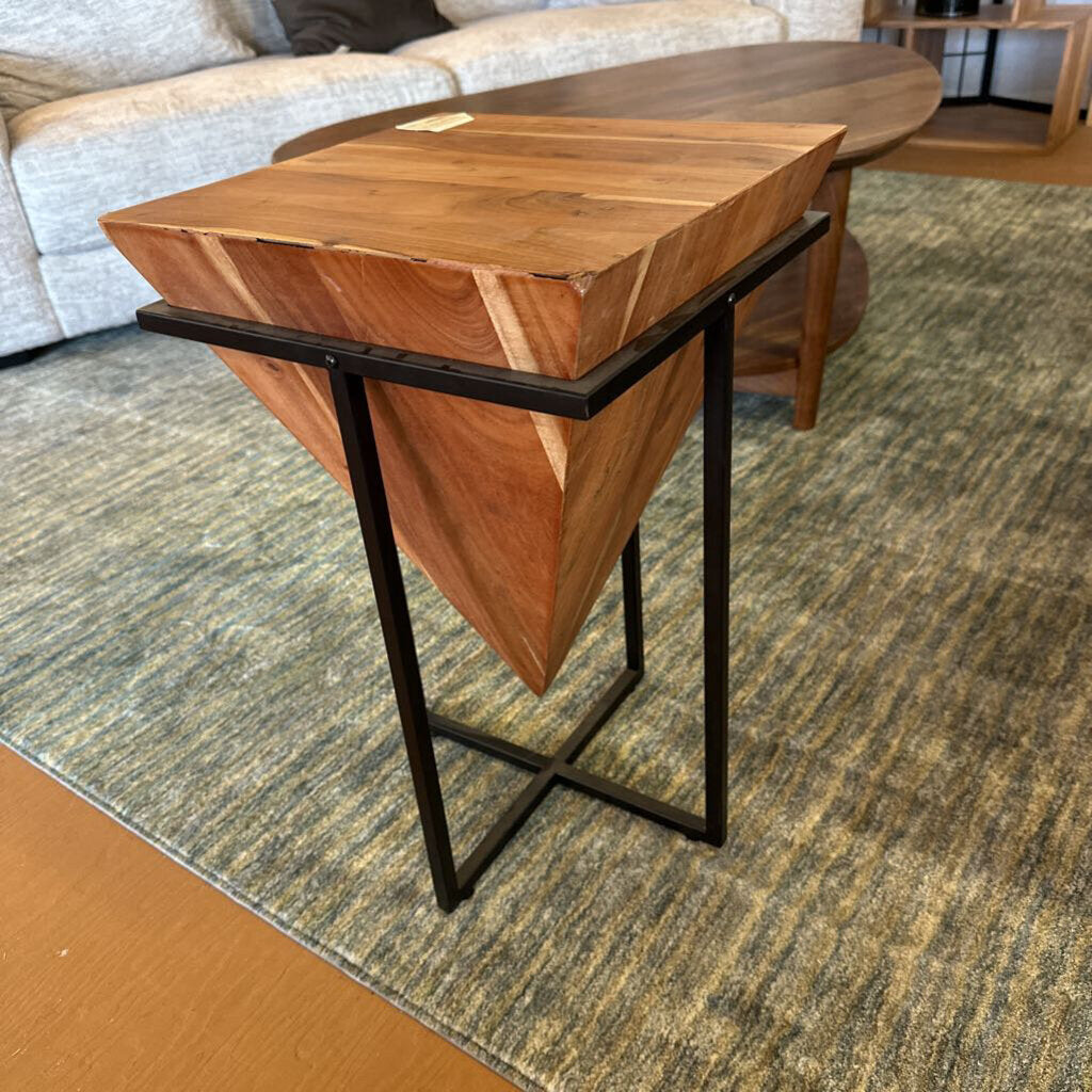 Wooden side table with black metal legs in a living room setting