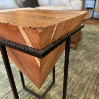 Wooden side table with black metal legs in a room setting