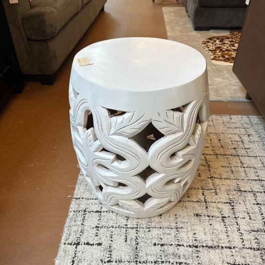 Decorative white stool with intricate patterns on a checkered rug