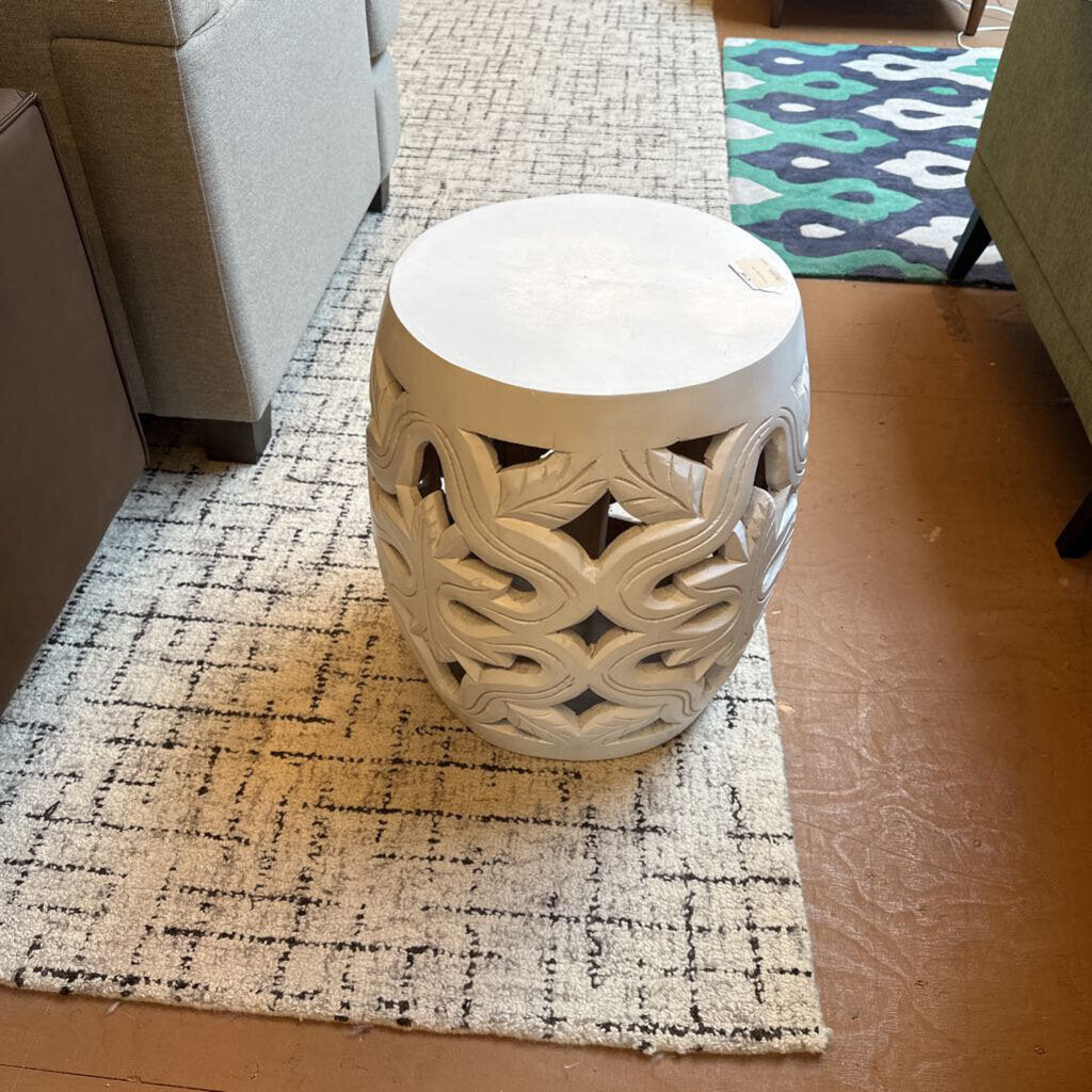 Decorative ceramic stool on a patterned rug in a living room setting