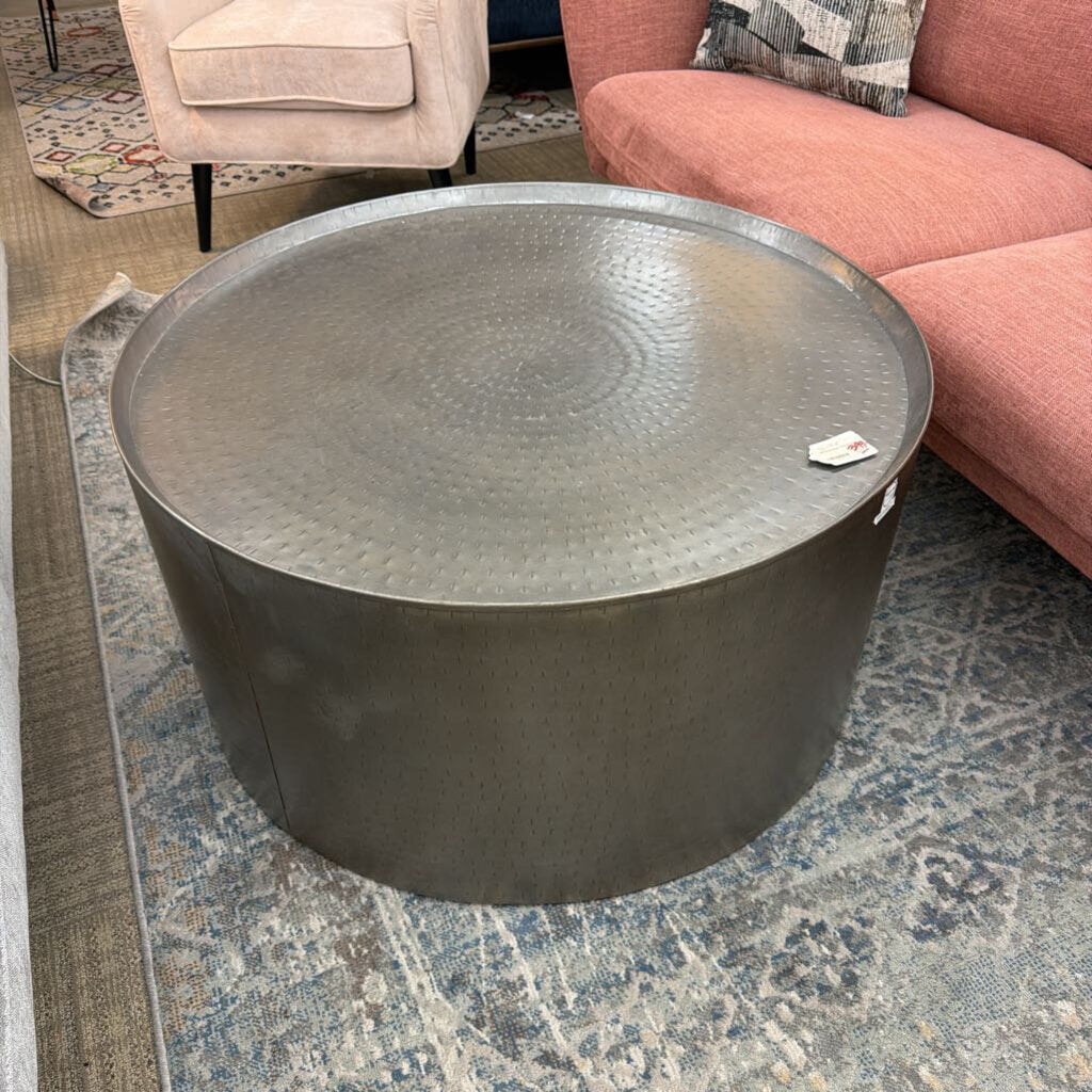 Round metal coffee table in a living room setting with a pink sofa and patterned rug.