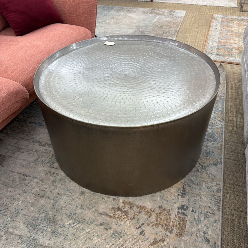 Round metal coffee table on a patterned rug with a red sofa in the background