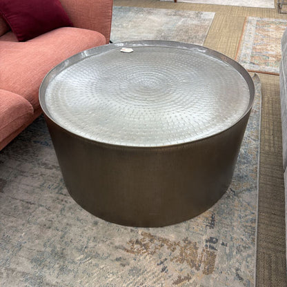Round metal coffee table on a patterned rug with a red sofa in the background