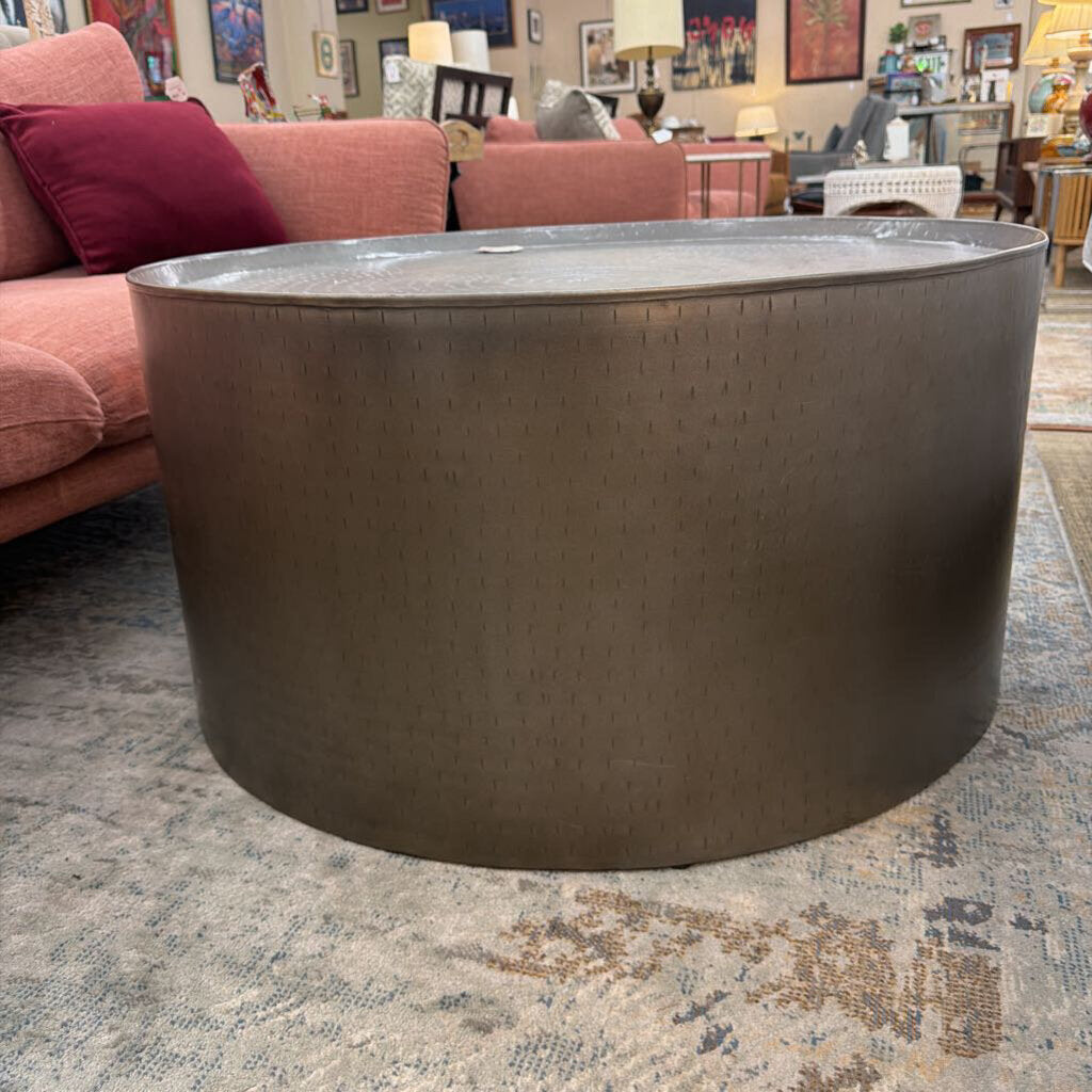 Round metallic table in a living room setting with a pink sofa and various decor items.