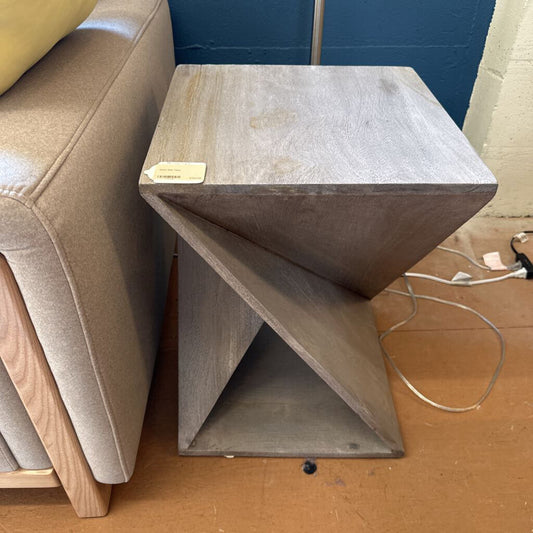 Gray side table next to a beige sofa with a blue wall in the background